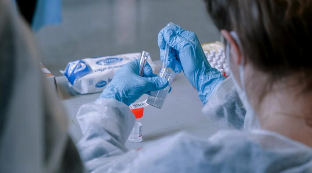 Technician handling test samples with gloved hands