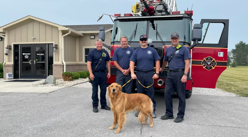 Four fire fighters and a dog in front of a Brownsburg fire truck in front of Brownsburg Animal Clinic