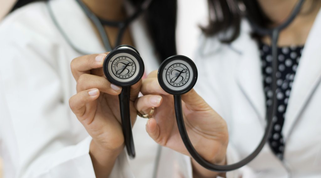 Two doctors' hands holding stethoscopes